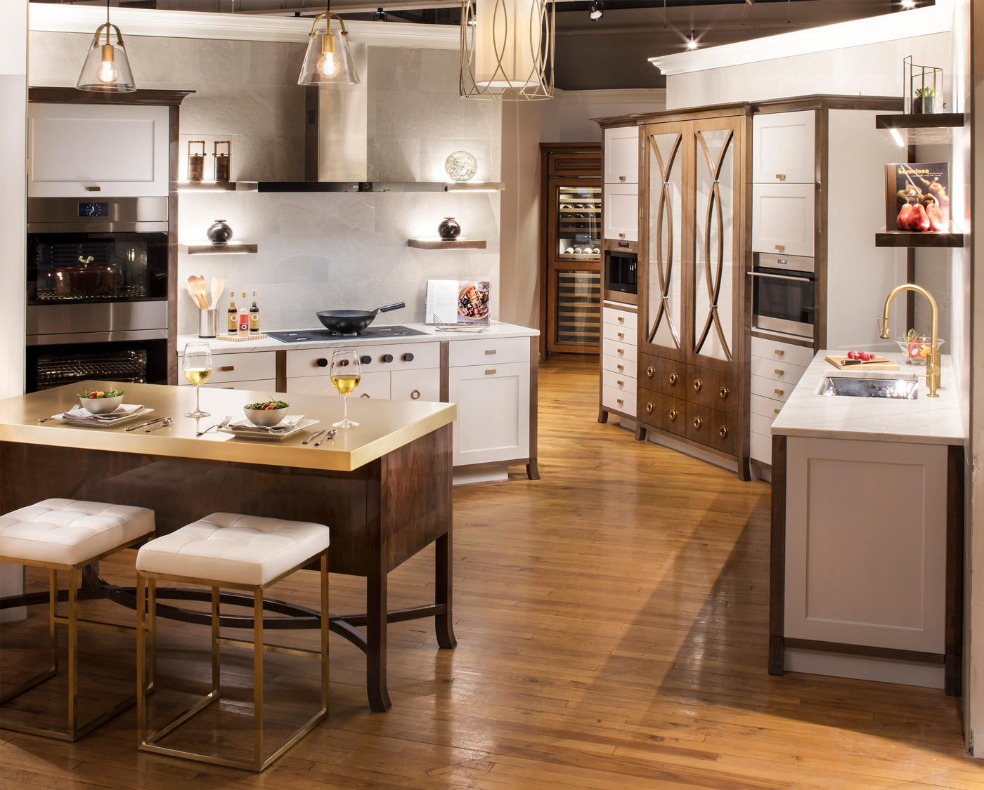 High end kitchen in Clarke showroom with island containing 2 stools and salads and wine 