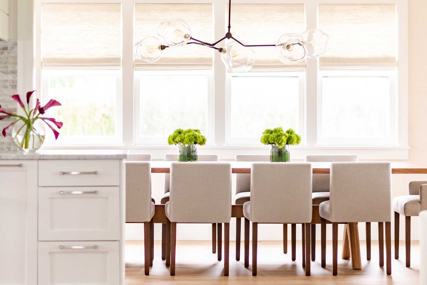 Kitchen table with greenery on top and wall of windows