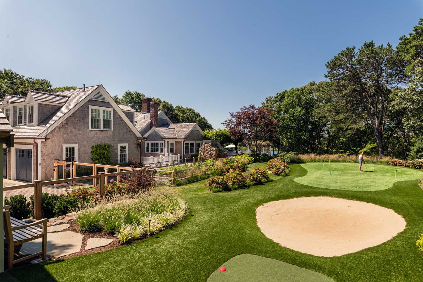 golf course with sand trap and person practicing next to a home