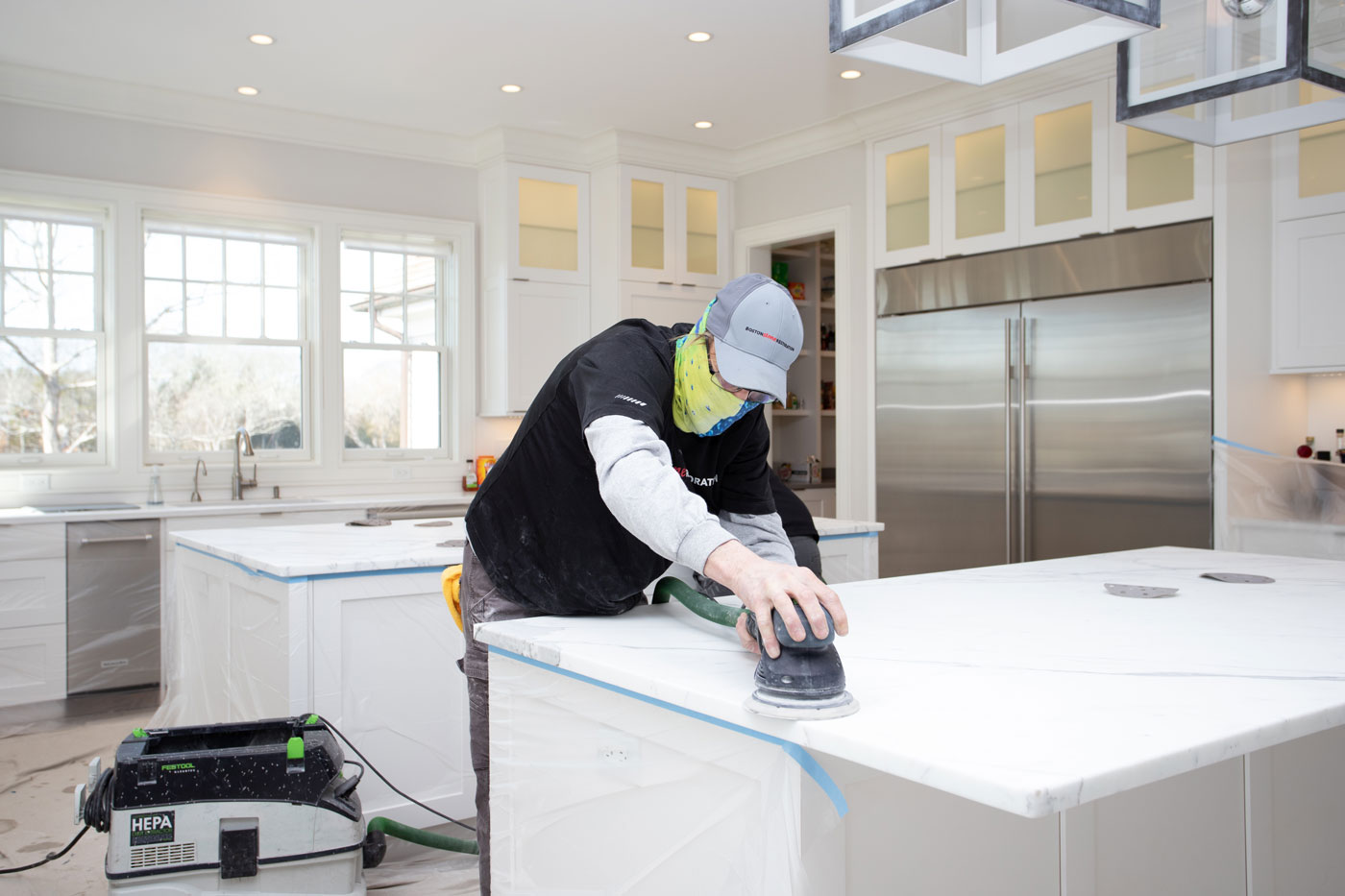 man in mask polishing kitchen countertop stone