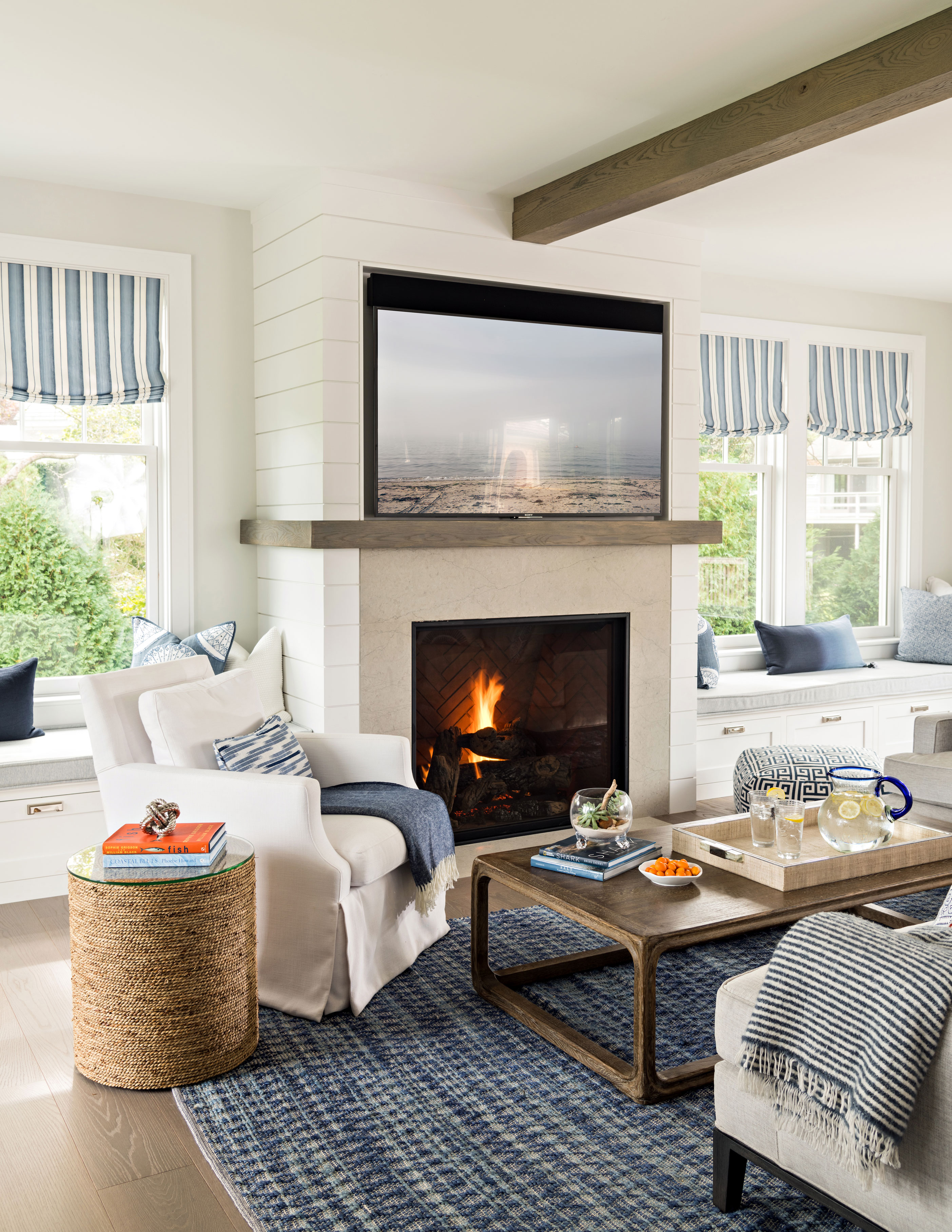 Family room with white furniture and shiplap fireplace with fire burning in fireplace