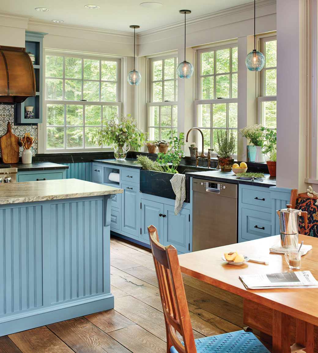 Bright blue farmhouse kitchen with apron sink and plants by CrownPoint