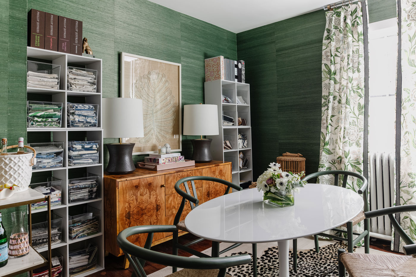 office with oval table in the center and green grasscloth phillip jeffries wallpaper