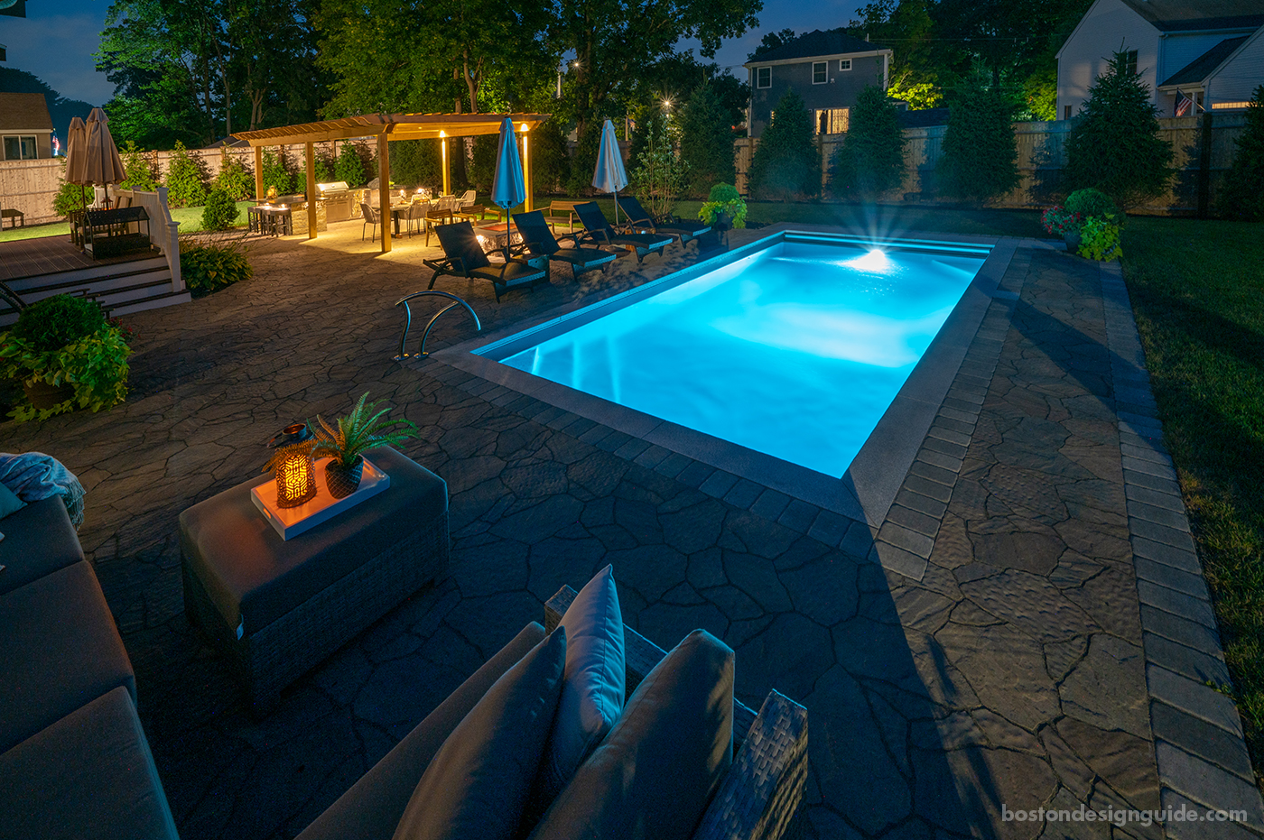 Residential pool terrace design at night by Land Design Associates