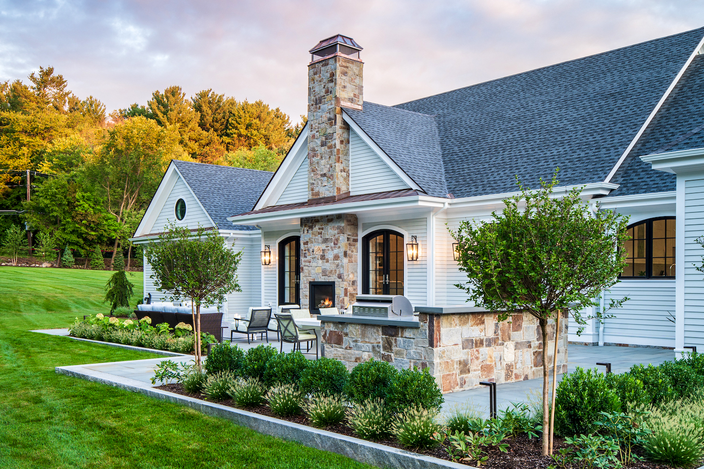 Outdoor patio with luscious landscape and stone grill and fireplace