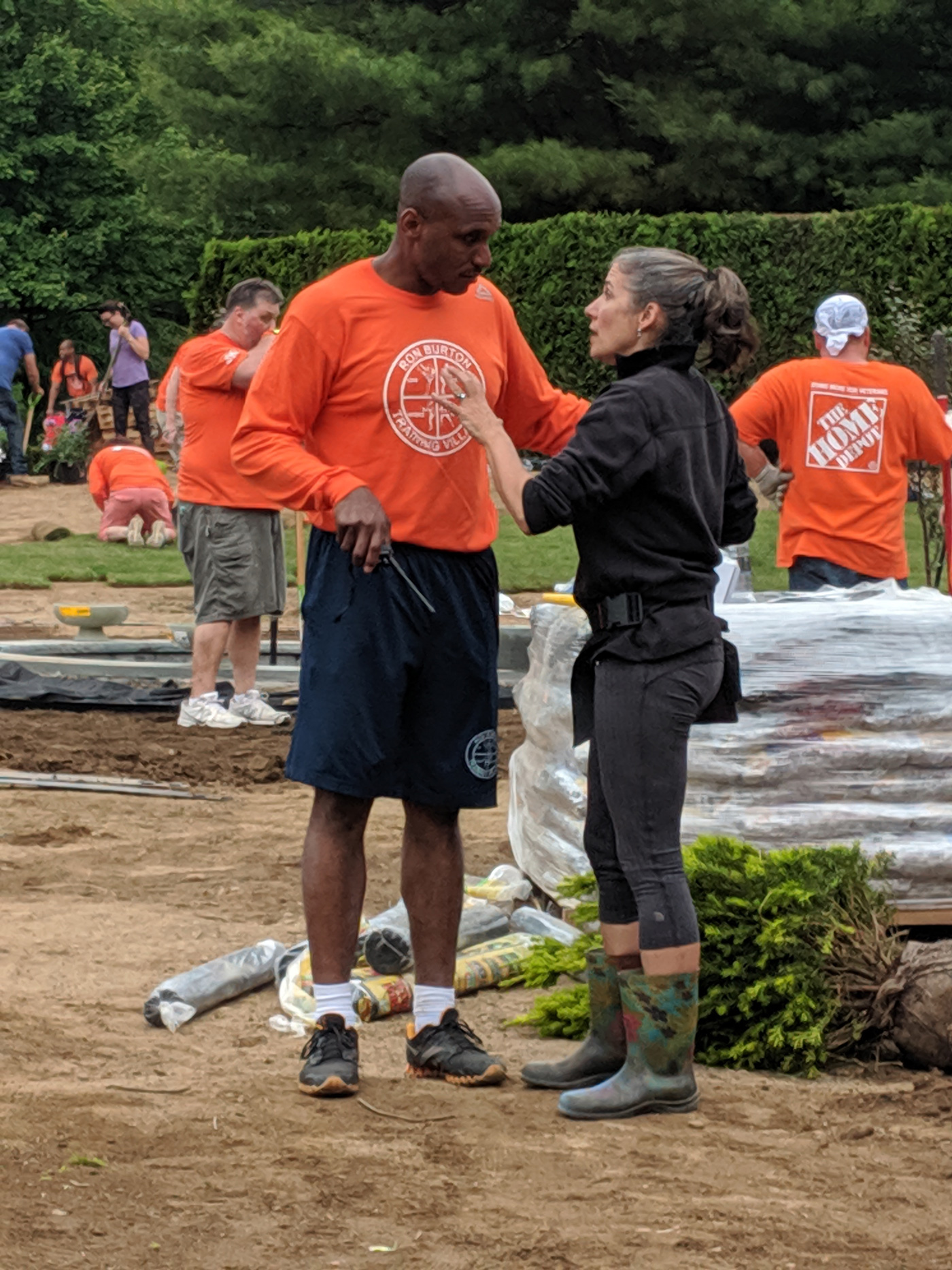 Man and Woman discussing landscaping project in front of workers