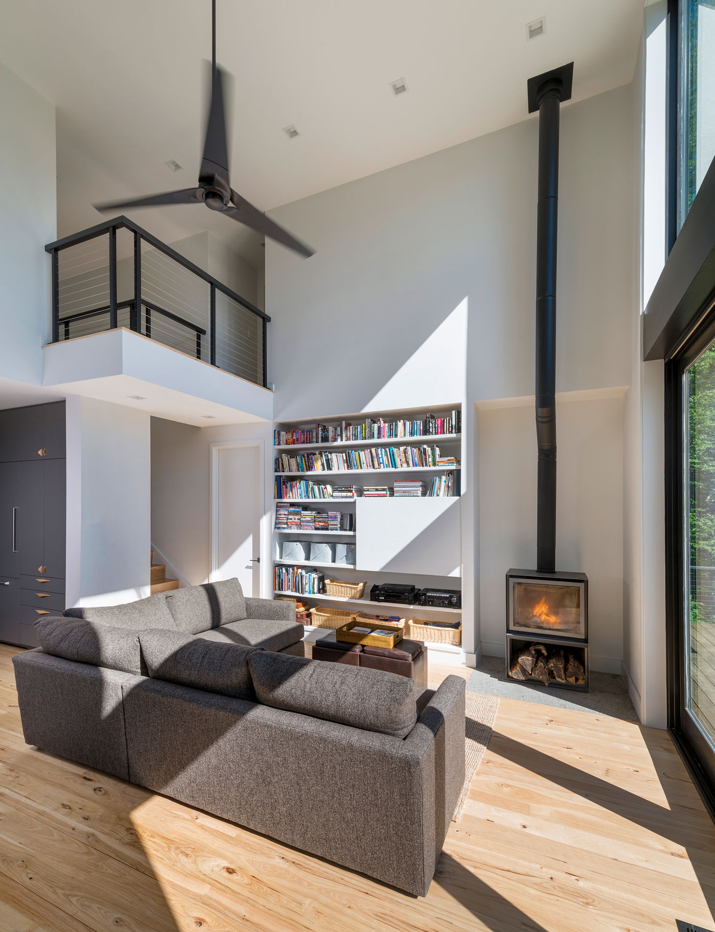 sleek living area with high ceilings a bookcase and a fireplace