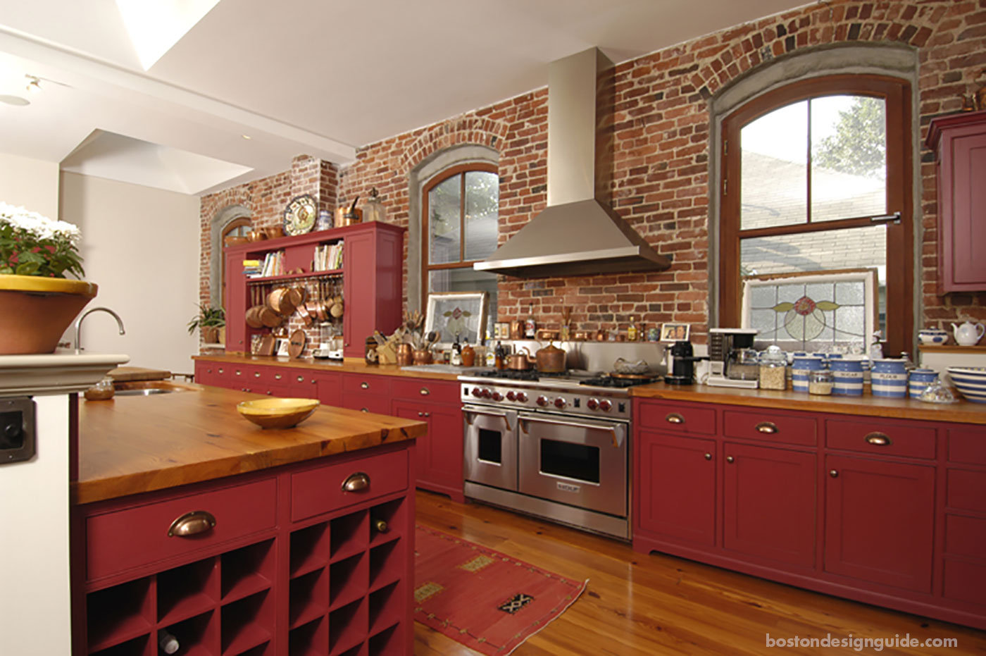 Red kitchen renovation with exposed brick by S+H Construction