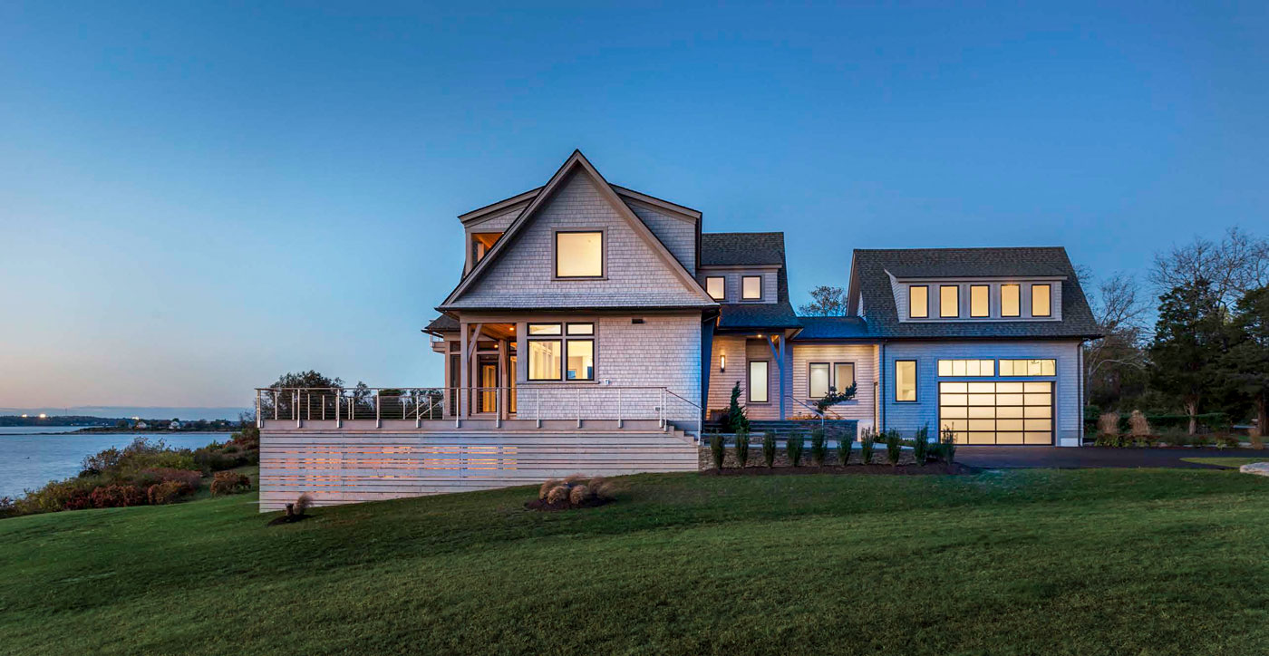 side view of custom home on the water at dusk