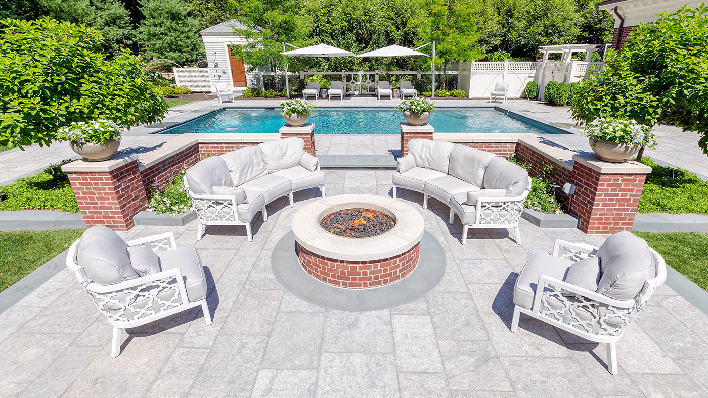 Limestone and brick pool and fire pit terrace by the Schumacher Companies