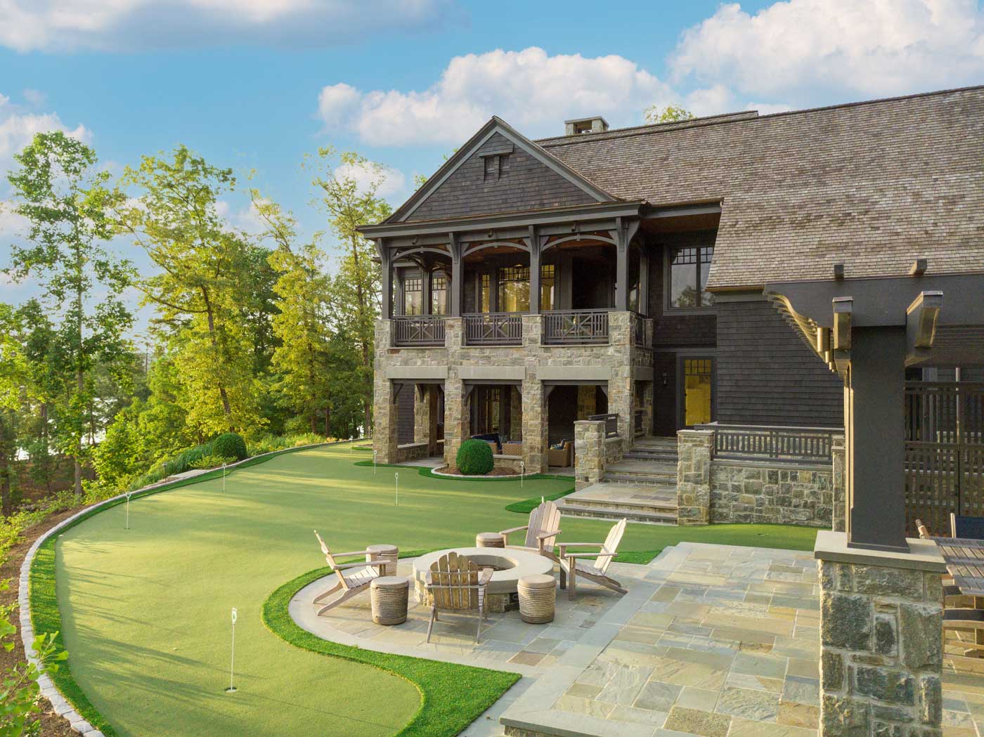 Backyard of house with putting green and fire pit and chairs 