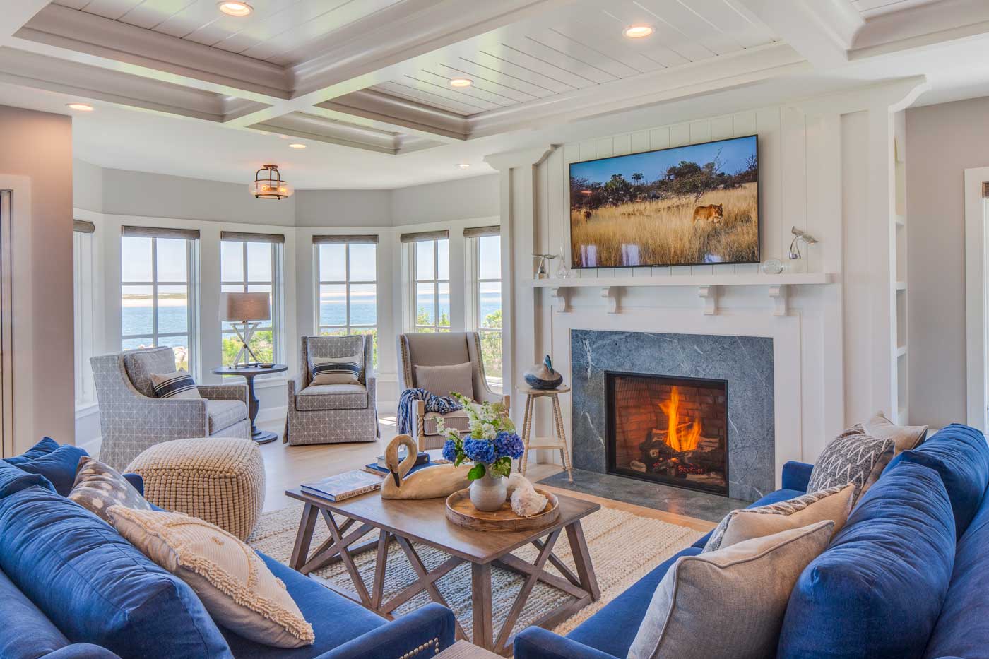 Family room with a fire burning, views of the ocean, blue sofas and custom ceiling