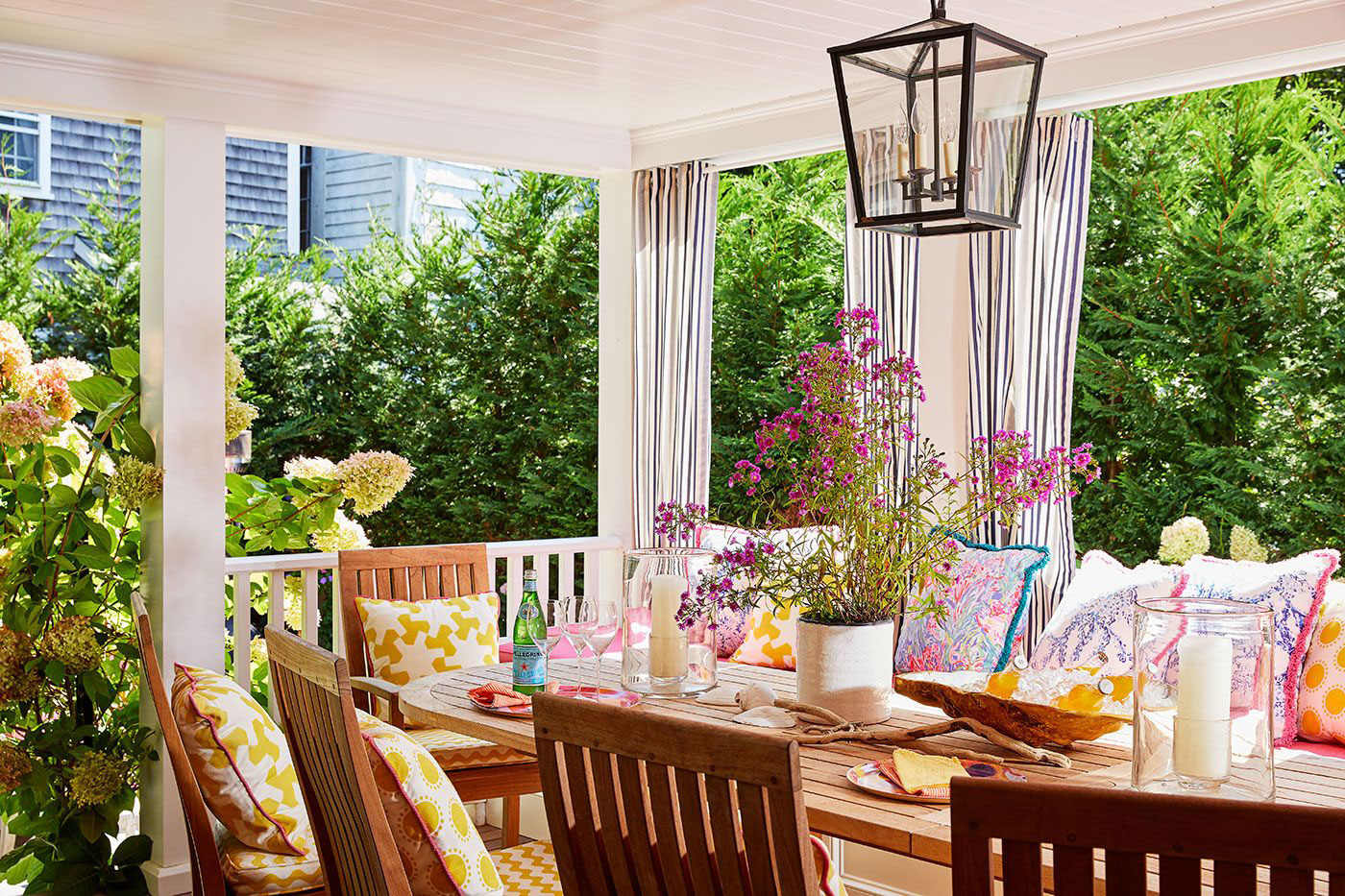 Porch with table and chairs surrounded by lush plantings