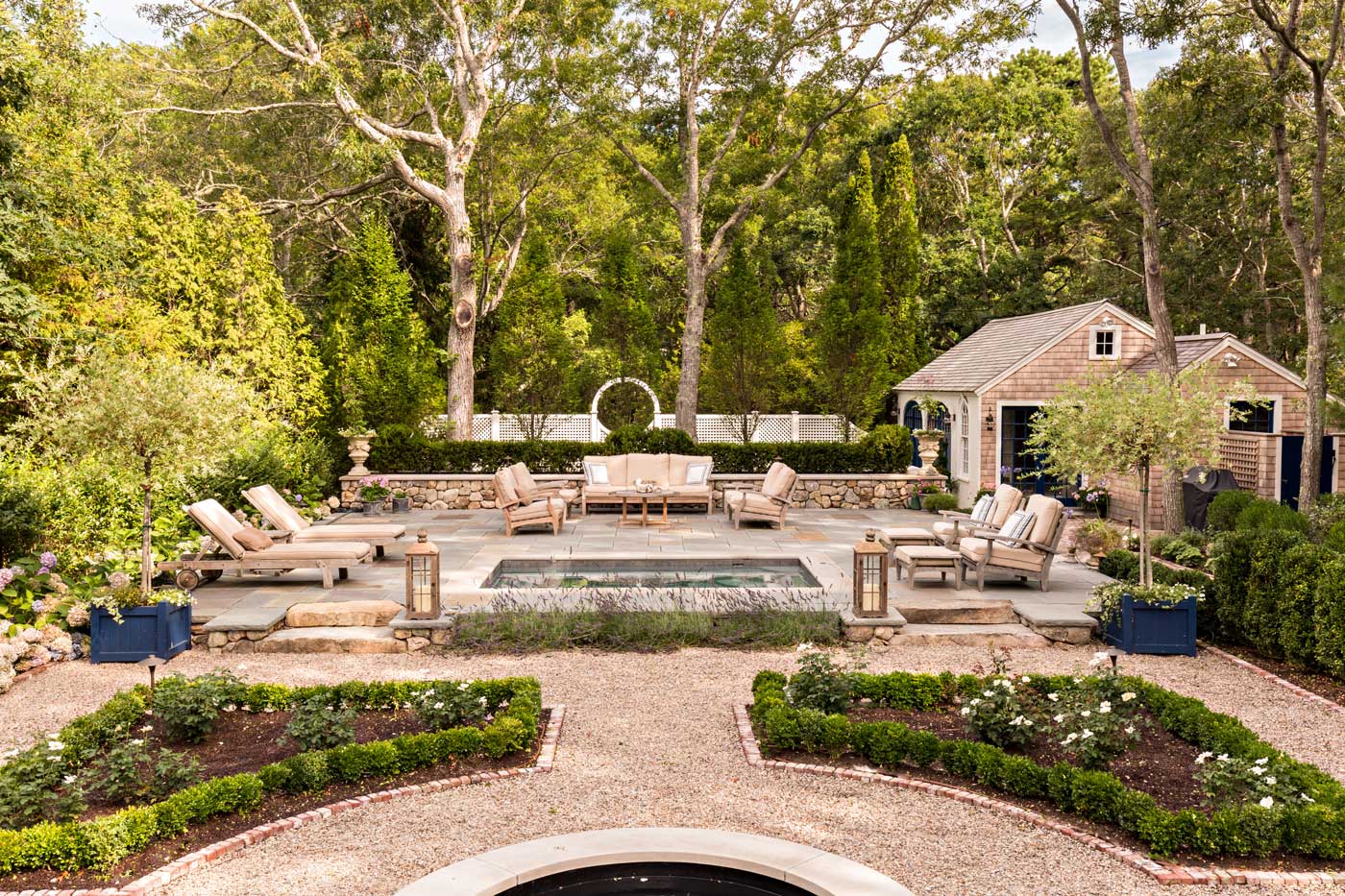 Backyard withreflecting pool and water feature are accented by stonewalls and parterre gardens with boxwoods and roses