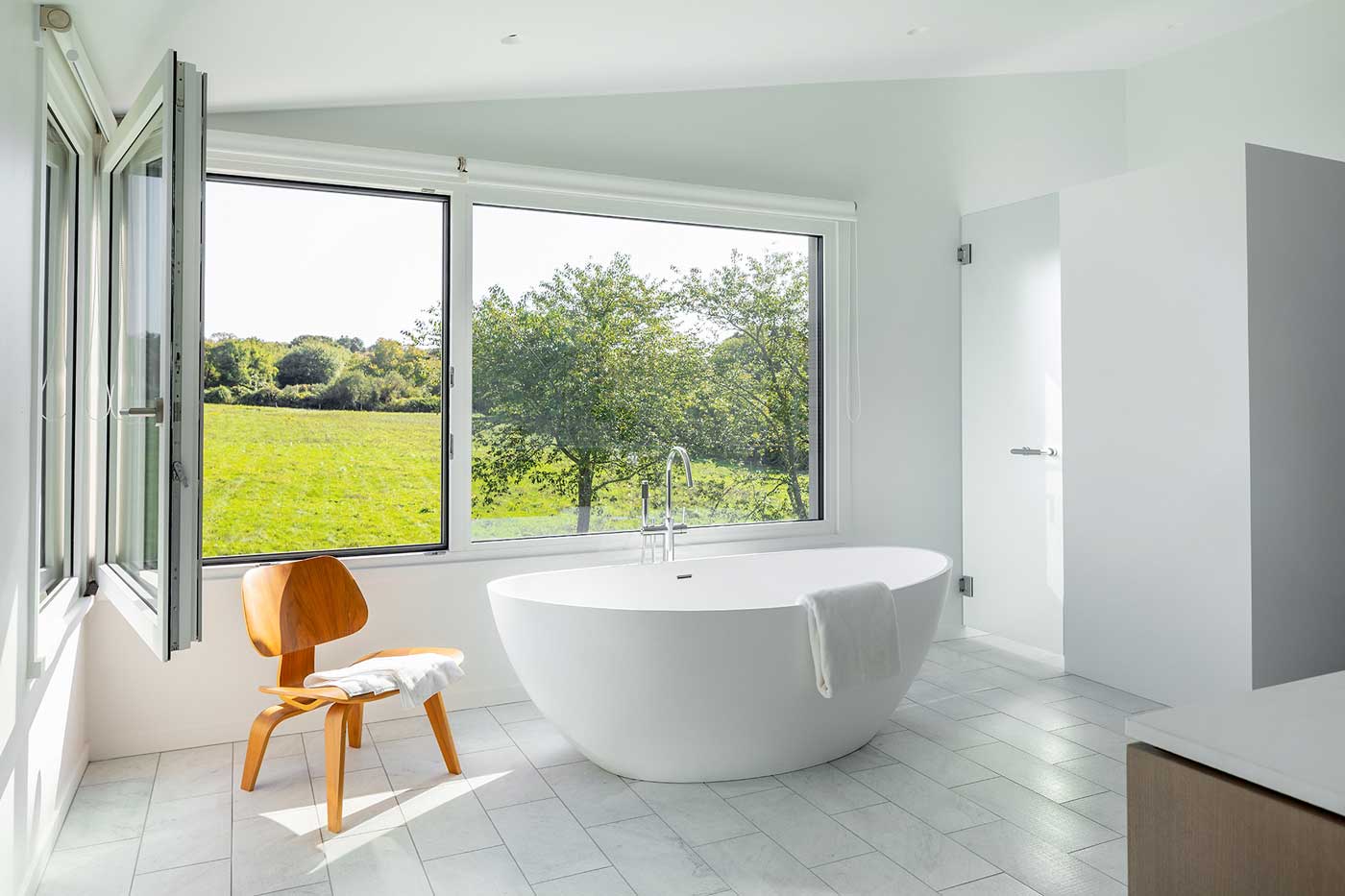 large white tub with a chair next to it and open window