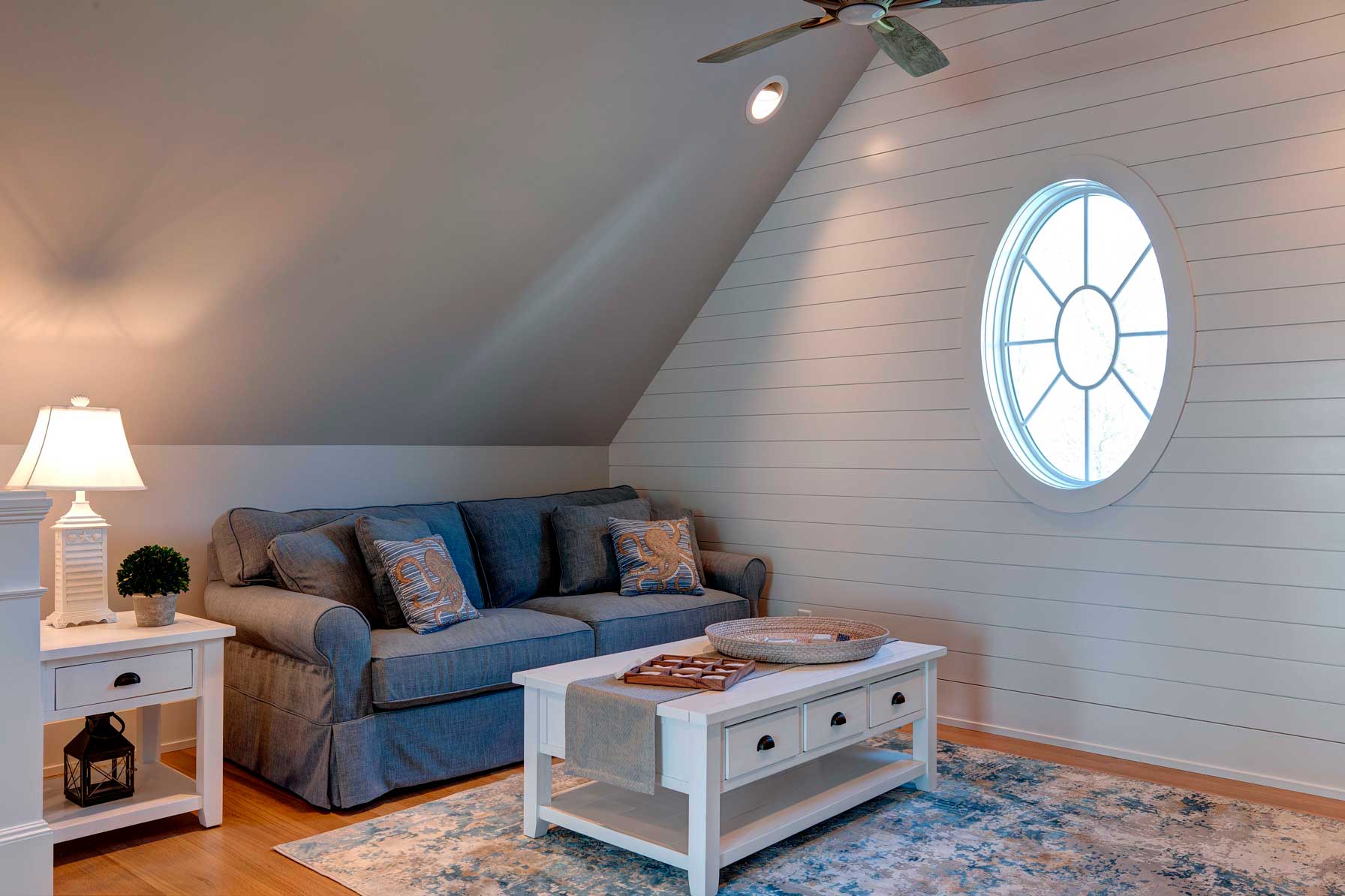 Living area with blue sofa and shiplap walls and circular window