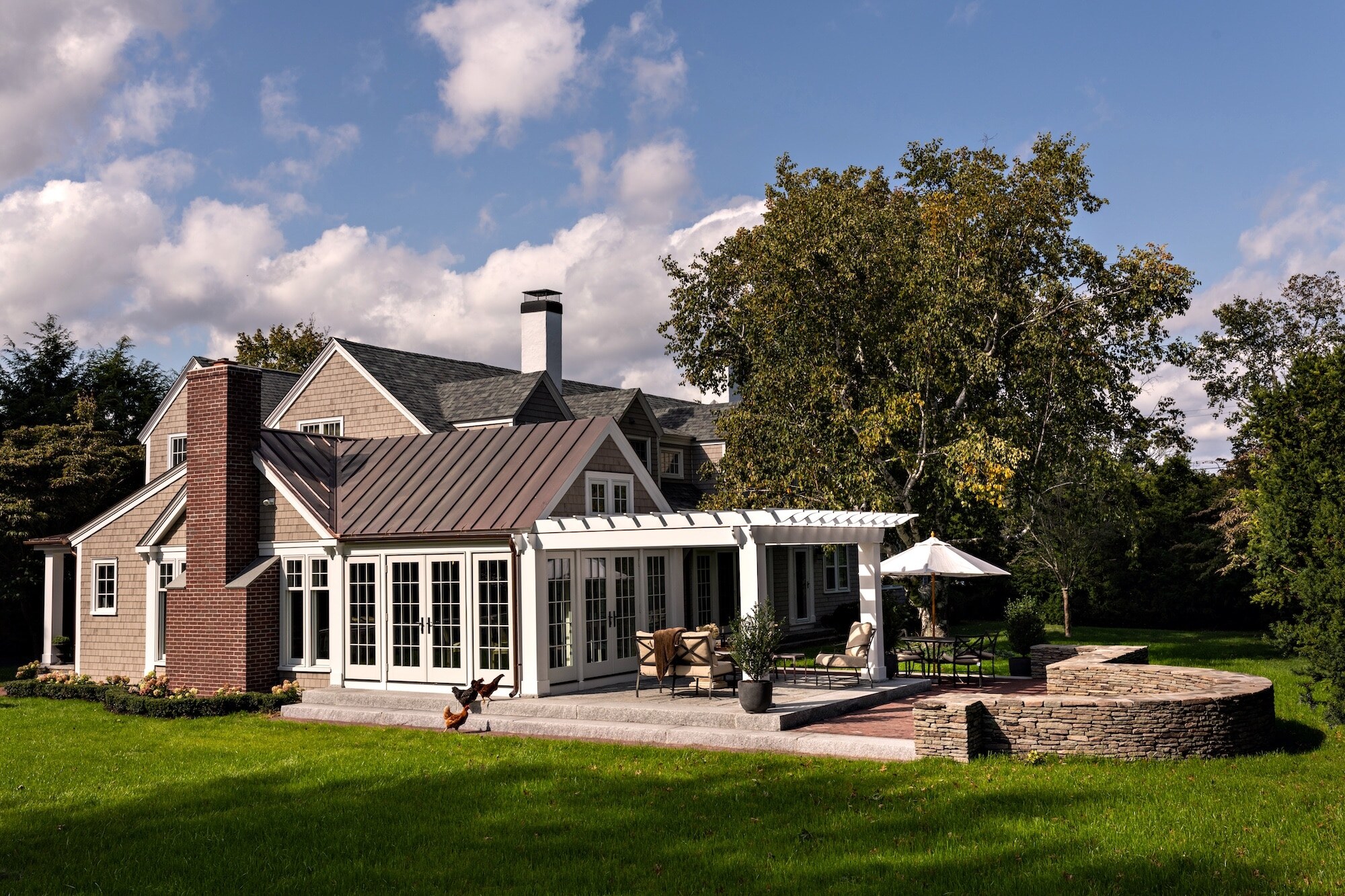 A conservatory addition featuring a pergola, stone wall, and adjoining patio. Photography: Dan Cutrona